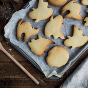 Shaped cookies on a baking tray with a wooden spoon