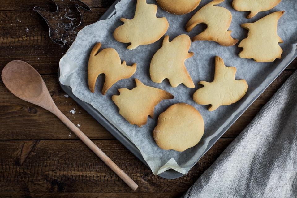 Shaped cookies on a baking tray with a wooden spoon